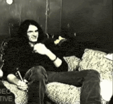 a black and white photo of a man sitting on a couch with the words video tive visible