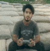 a man wearing a west coast shirt holds a video game controller