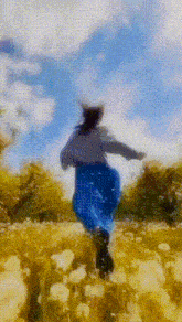 a woman in a blue skirt is running through a field of yellow flowers