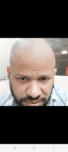 a close up of a man 's face with a bald head and a beard .