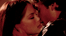 a close up of a man and woman kissing with their eyes closed