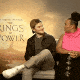 two people sitting in front of a poster for the lord of the rings