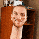 a man with a very long neck is smiling in front of a shelf with funko pops on it .