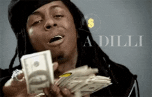 a man with dreadlocks is holding a stack of money in his hand .
