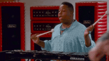 a man in a blue shirt is playing a xylophone