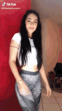 a woman in a white crop top and zebra print pants is standing in a room .