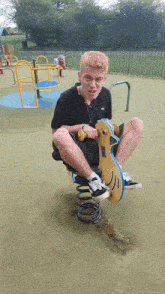 a boy sits on a rocking horse in a park