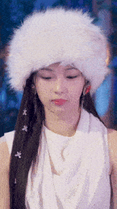 a woman wearing a white fur hat and earrings looks down