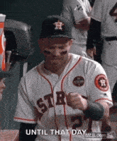 a man in a baseball uniform is standing in a dugout and making a fist .