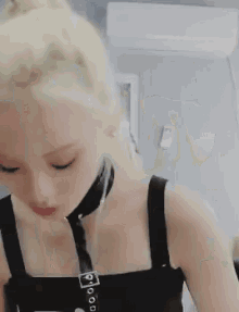 a woman wearing a choker and a black tank top is looking down at her phone .