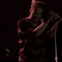 a man singing into a microphone with a necklace around his neck