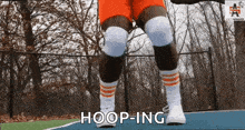 a person wearing orange shorts and white socks is standing on a basketball court and says hoop-ing