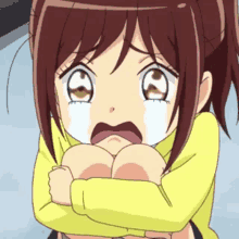 a little girl is crying while hugging her knees and looking at the camera .