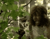 a man with a beard is standing in the woods looking at something .