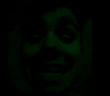 a close up of a person 's face in the dark with their eyes glowing green .