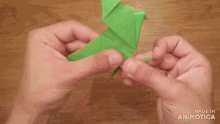 a person is holding a green origami bird in their hands