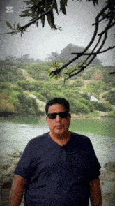 a man wearing sunglasses is standing in front of a lake
