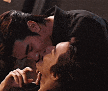 a man is kissing another man on the cheek while laying down .
