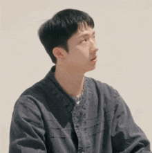 a young man wearing a black jacket is sitting in front of a wall .