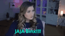 a woman sitting in front of a screen that says jaja binx !!!