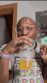 a man wearing glasses is drinking from a plastic cup
