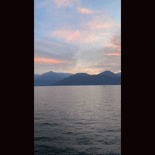 a lake with mountains in the background and a pink sky