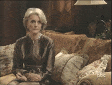 a woman is sitting on a couch with abc written on the bottom