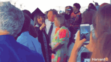 a woman taking a picture of a graduation ceremony with the word harvard on the bottom