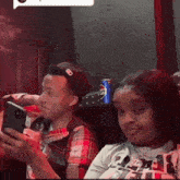 a man and a woman are sitting next to each other looking at their phones