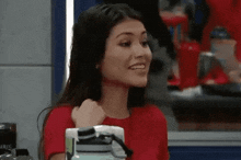 a woman in a red shirt is smiling while holding a water bottle in her hand .