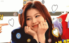 a woman with red hair and a ring on her finger is smiling with hearts and flowers surrounding her .