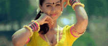 a woman in a yellow top is making a funny face with her hands .