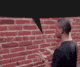 a man stands in front of a red brick wall with a speech bubble above him
