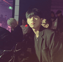 a man in a black jacket is sitting in a crowded room