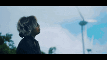 a person looking up at a wind turbine in the distance