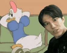 a man is sitting next to a cartoon duck on a green couch
