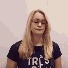a blonde woman wearing glasses and a shirt that says tres