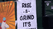 a sign that says rise and grind it 's hanging on a wall