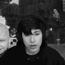 a man wearing headphones and a black hoodie looks at the camera
