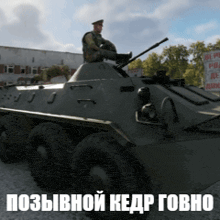 a man is sitting on top of a military vehicle with russian writing on the bottom