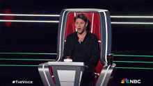 a man is sitting in a chair with a nbc logo in the corner