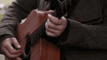 a man is playing an acoustic guitar with a capo on it