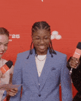 a woman in a blue jacket stands in front of a red background that says aft 25