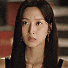 a close up of a woman 's face with long hair and a necklace .