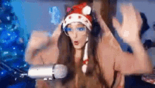 a woman in a santa hat is sitting in front of a microphone .