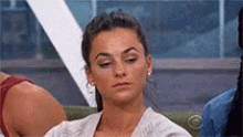 a woman is sitting on a couch with her eyes closed and a serious look on her face .