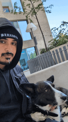 a man wearing a beanie that says blazer holds a dog