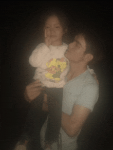 a man is holding a little girl who is wearing a minnie mouse sweater