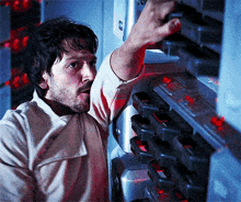 a man with a beard is reaching for a button on a wall .