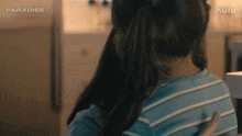 a girl with a ponytail is hugging another girl in a striped shirt .